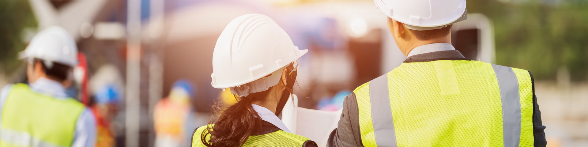 business people in high visibility vests looking at plans on construction site