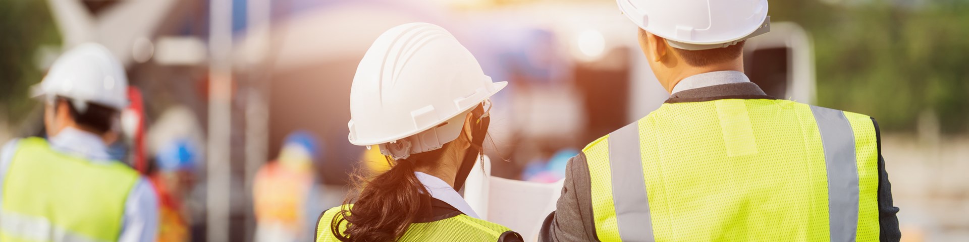 business people in high visibility vests looking at plans on construction site 