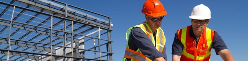 two men on a building site looking at construction plans