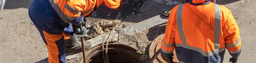 Drainage workers carrying out work down a man hole